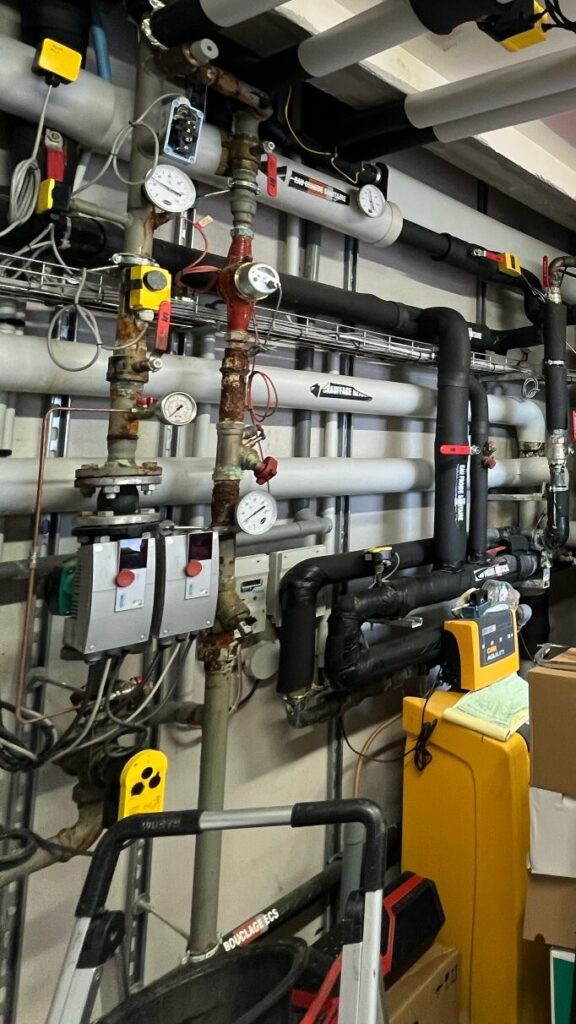 Réseau hydraulique avec circulateurs, manomètres et équipements de régulation dans un local technique réseau de traitement de l'eau